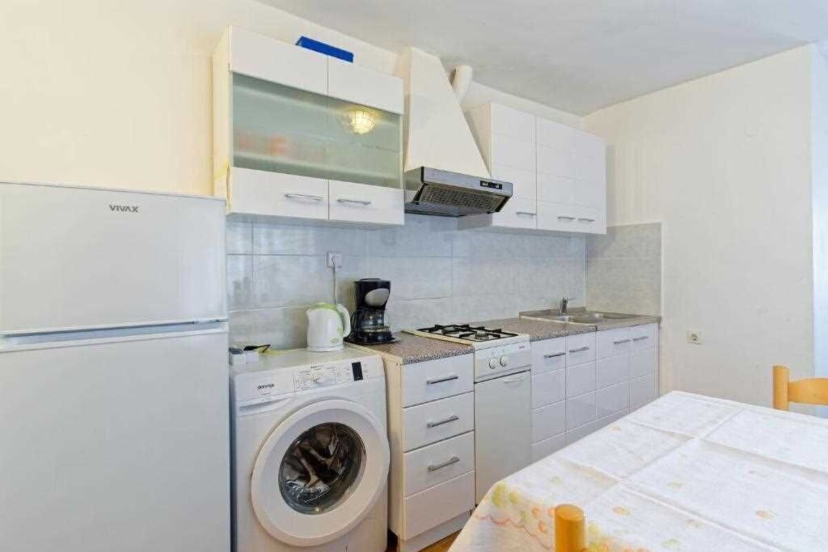 A compact kitchen with a washing machine, a coffee maker, and a stove.