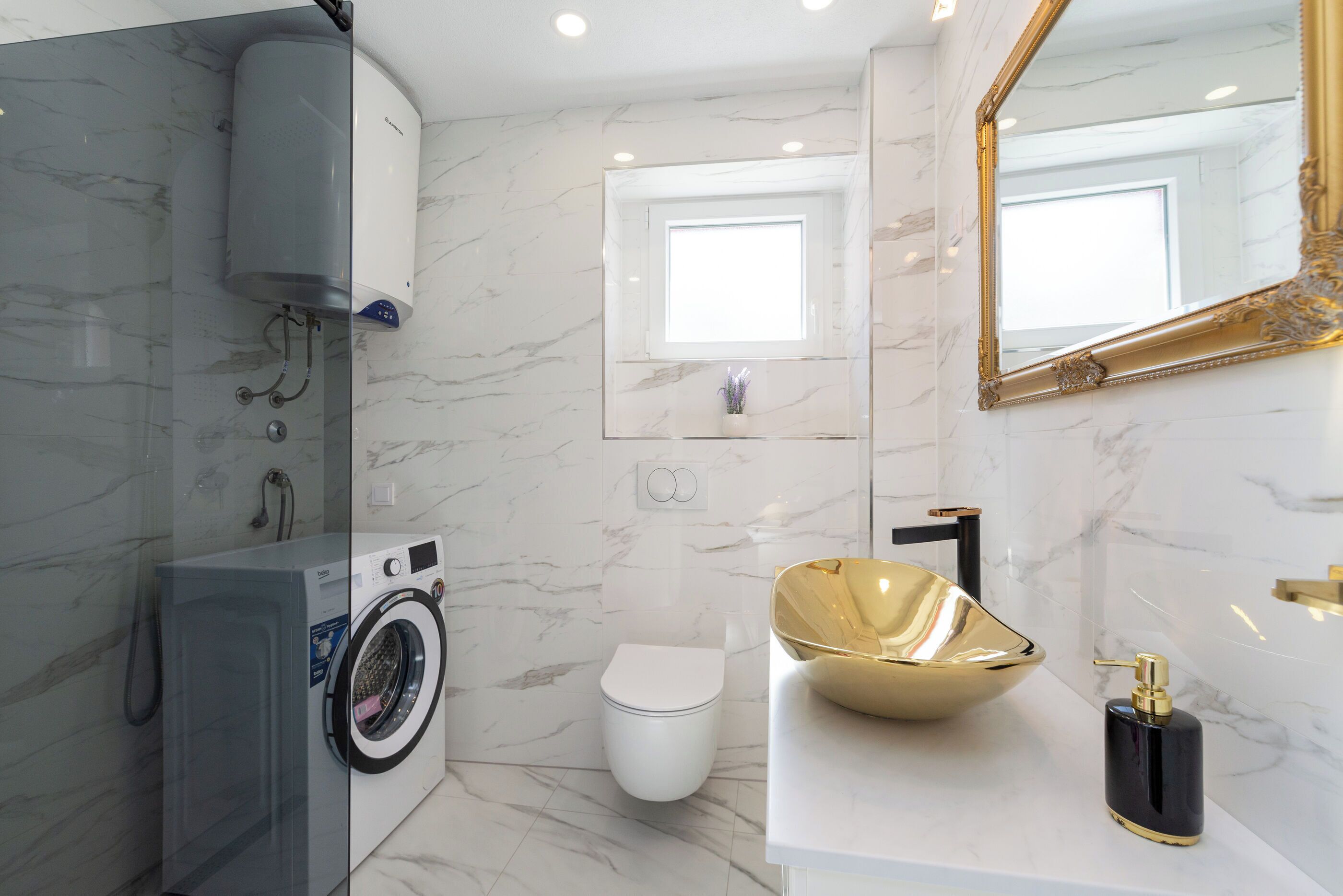 A modern bathroom with a washing machine, toilet, and a large gold sink.