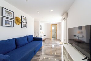 Ein modernes Wohnzimmer mit einem blauen Sofa, einem Flachbildfernseher und gerahmten Bildern an der Wand.
