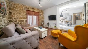 A living room with a stone wall, a sofa, a coffee table, and a yellow armchair. - Villa Dalmatian Dream (Benkovac)