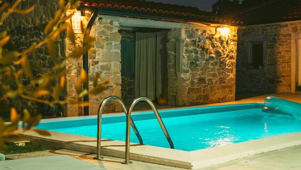 A stone pool with a ladder, surrounded by lounge chairs and a stone building. - Villa Dalmatian Dream (Benkovac)