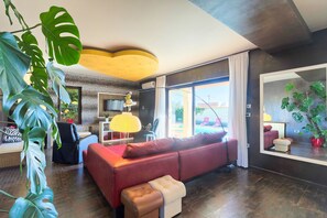 A modern living room with a red sofa, a large mirror, and tropical plants. - Villa Aldo (Vodnjan)