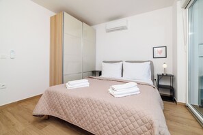 A bedroom with a bed, a bedside table, a nightstand, a wardrobe, and a window. - Villa The View (Crikvenica)