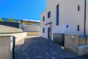 Un edificio moderno con un patio empedrado, una entrada con reja y una puerta a la vista.