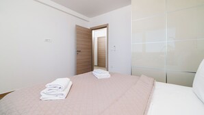 Ett hotellrum med en säng, en garderob och en dörr som leder till ett annat rum.