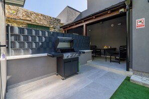 An outdoor kitchen area with a grill, a small table, and a chair. - Villa Hermosa (Vinodol)