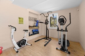 Ein Heimfitnessraum mit einem Crosstrainer, einem stationären Fahrrad und einem Laufband.