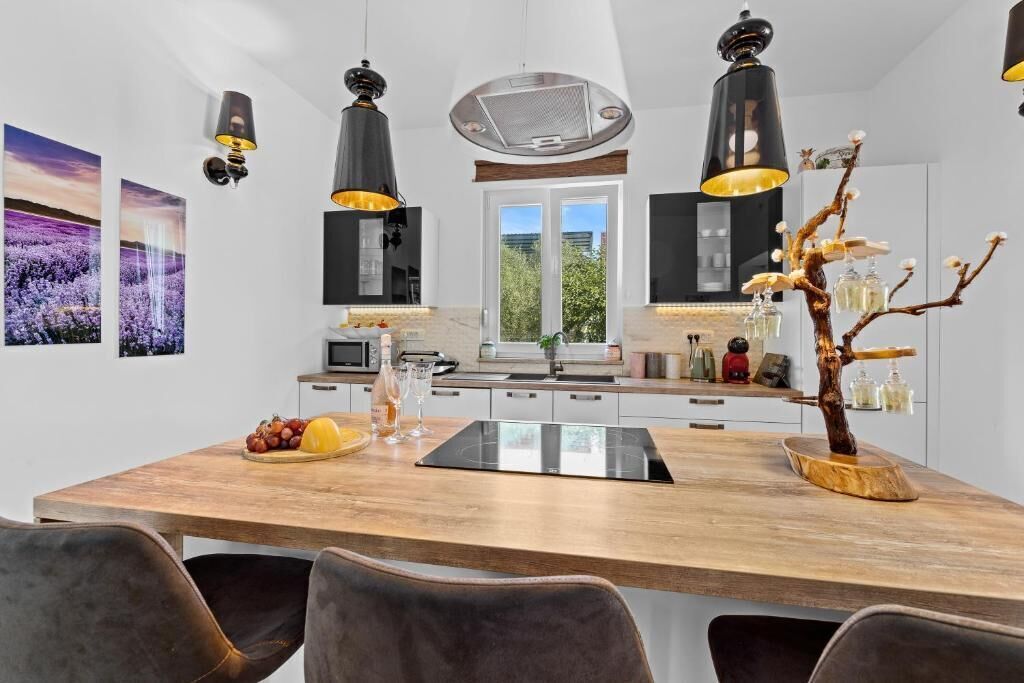 Een moderne keuken met een houten kookeiland, hanglampen en uitzicht op het terras.
