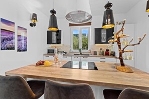 Eine moderne Küche mit einer Holzinsel, Pendelleuchten und Blick ins Freie.