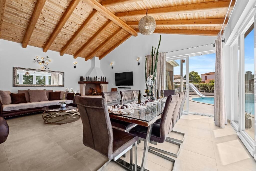 A spacious living area with a dining table, sofas, and a poolside view.