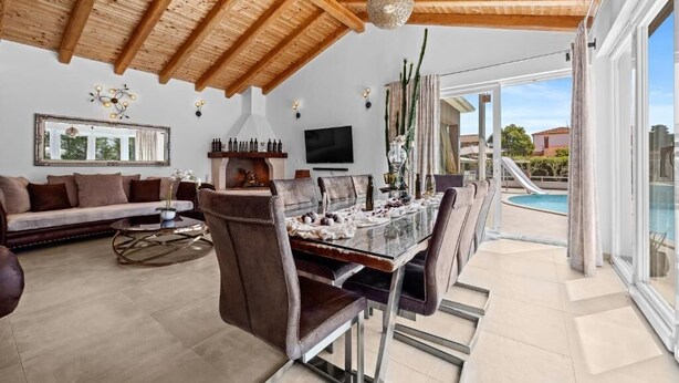 Àmplia zona d'estar amb taula de menjador, sofàs i vista cap a la piscina.