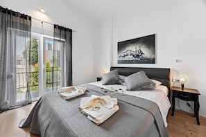 Ein Schlafzimmer mit Bett, Vorhängen, einem Nachttisch, einer Lampe und einem Bild an der Wand.