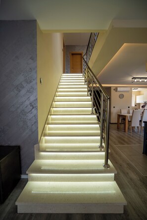 Eine Treppe mit Metallgeländer, die zu einem Raum mit Essbereich und einer Wanduhr führt.