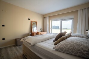 Ein Schlafzimmer mit einem großen Bett, einem Schminktisch, einem Spiegel und einem Fenster mit Blick.