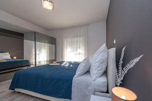 Ein modernes Schlafzimmer mit einem großen Bett, einem Nachttisch, einem Spiegel und einem Fenster mit Vorhängen.