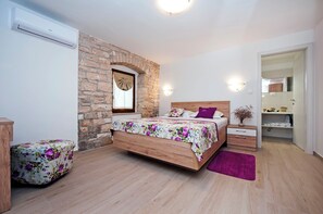 Ein Schlafzimmer mit einem hölzernen Bett, einer Steinwand, einem kleinen Nachttisch und einem Beistelltisch.