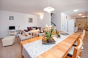 Ein modernes Wohnzimmer mit Sofa, Esstisch und einer Treppe zu einer weiteren Ebene.