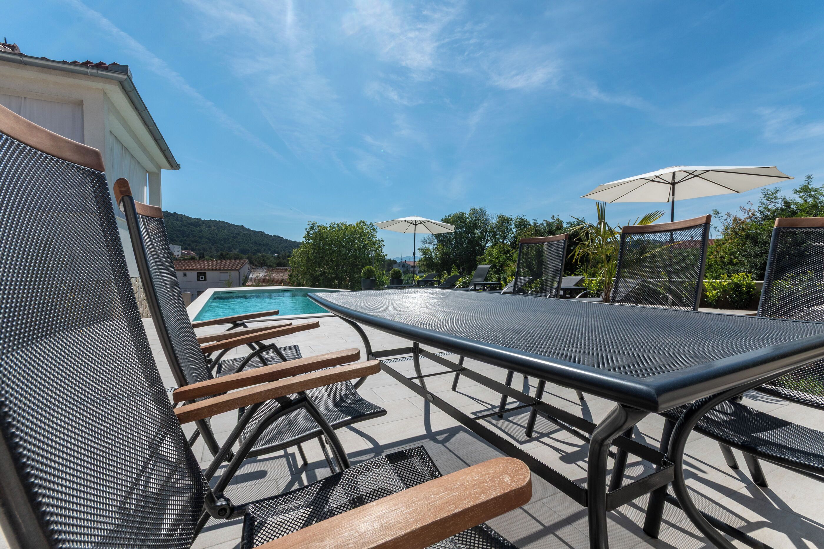Ein Poolbereich mit Liegestühlen, einem Tisch und Sonnenschirmen.