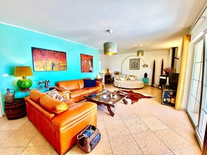 Ein Wohnzimmer mit einer Couch, einem Couchtisch und einem Bett im Hintergrund.