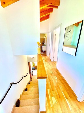 Un escalier menant à une salle de bain où l’on trouve un miroir et un tableau encadré au mur.