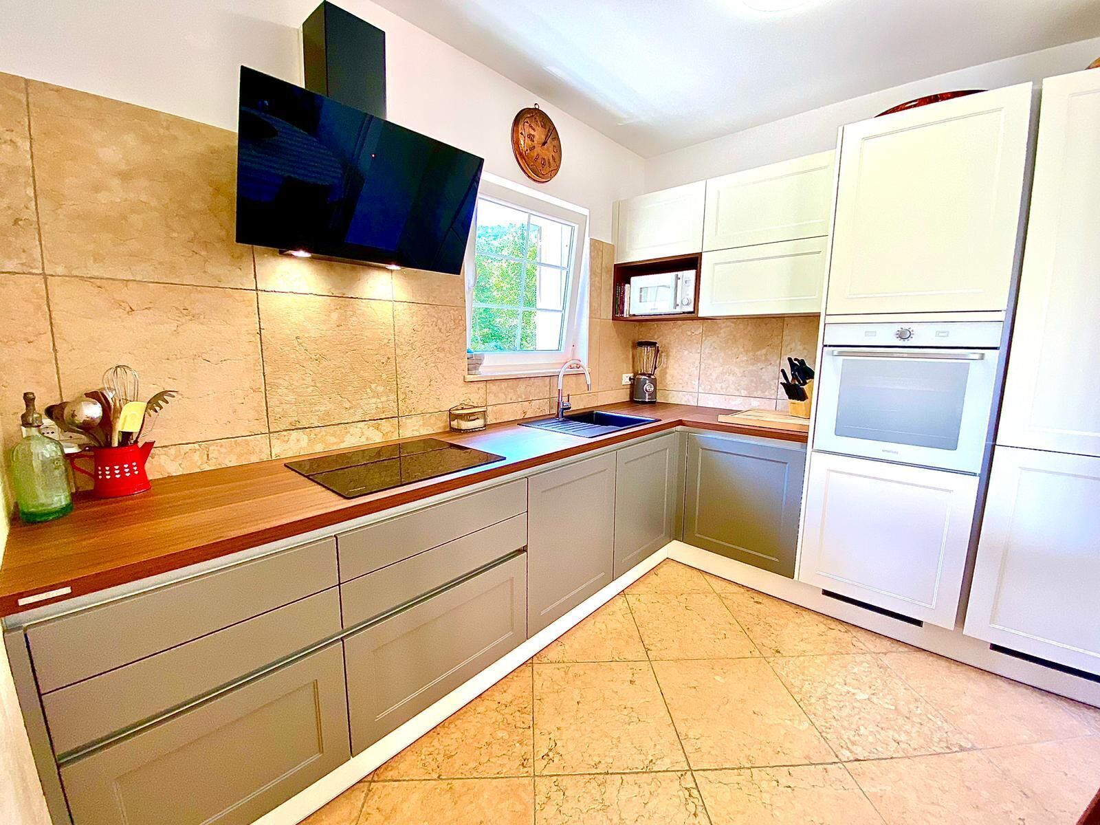 A kitchen with a built-in oven, microwave, and a large window.