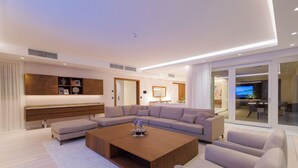 Una sala moderna con un sofá seccional, una mesita de centro y un mueble empotrado para entretenimiento.