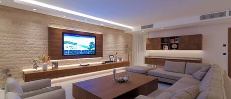 Ein modernes Wohnzimmer mit Flachbildfernseher, Couchtisch aus Holz und einem Ecksofa.