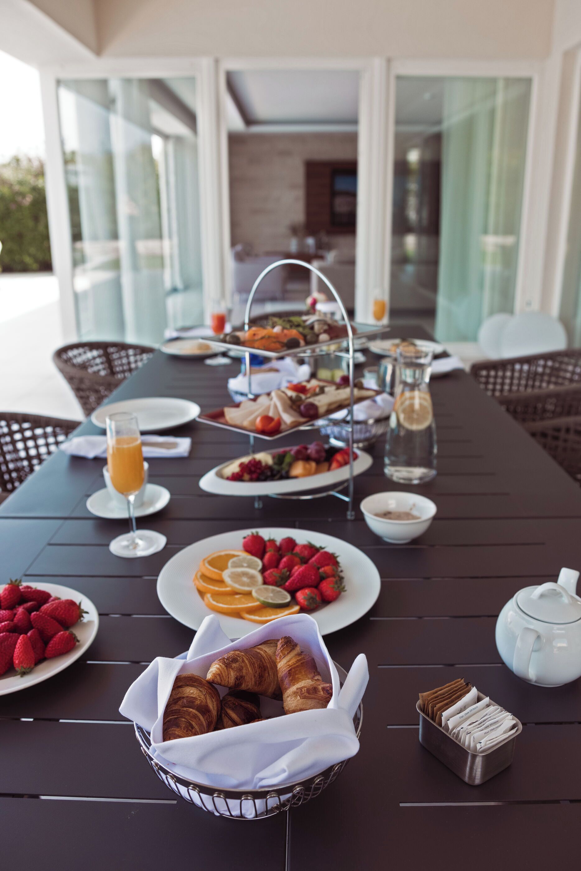 Un buffet de petit-déjeuner avec des croissants, des fraises et des tranches d’orange, le tout disposé sur une table.