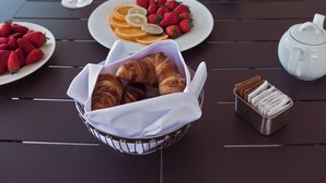 Un bufé de desayuno con cruasanes, fresas y gajos de naranja sobre una mesa.