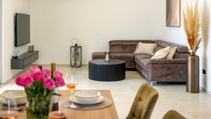 Una sala de estar moderna con un sofá, una mesa de centro y un comedor con una mesa dispuesta para dos personas.