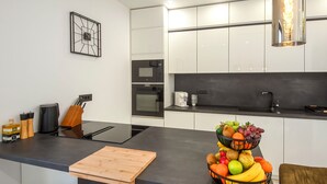 Una cocina moderna con una isla central, un cuenco de fruta y un reloj en la pared.