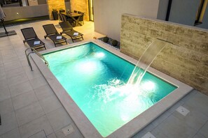 Ein Pool mit Wasserfall, Liegestühlen und einem Essbereich.