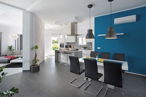 Eine moderne Küche mit blauer Akzentwand, einem Essbereich mit schwarzen Stühlen und einer großen Kochinsel.
