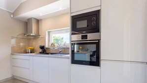Una cucina moderna con mobili bianchi, forno integrato e microonde.