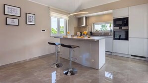 Una cucina moderna con isola centrale, sgabelli da bar e forno a microonde.
