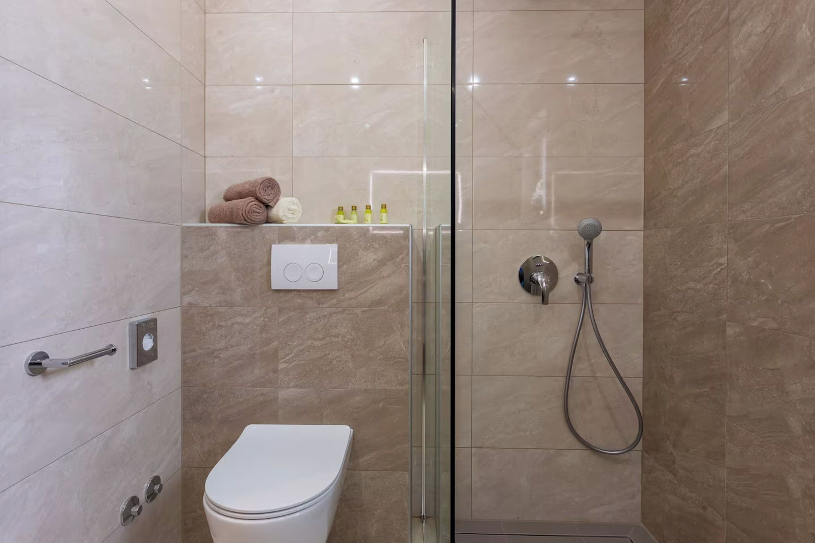 A modern bathroom with a glass-enclosed shower, a toilet, and a towel rack.