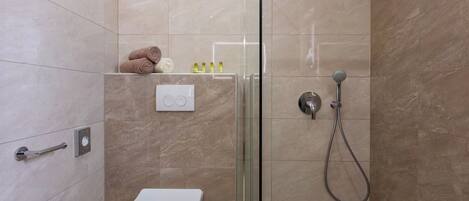 A modern bathroom with a glass-enclosed shower, a toilet, and a towel rack.