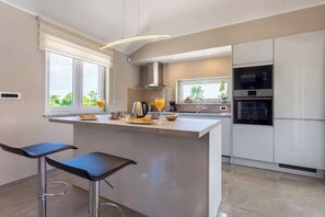 Una cocina moderna con una isla central, taburetes de bar y electrodomésticos integrados.