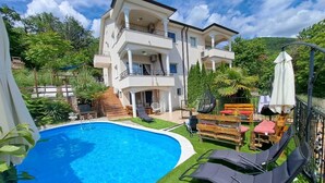 Un edificio de dos pisos con piscina, mobiliario exterior y jardín.