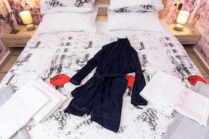 A double bed with a patterned bedspread, two bedside lamps, and a nightstand with a lamp. - Villa Emily (Opatija)