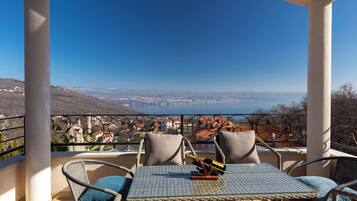 A balcony with wicker chairs, a table, and a bottle of champagne.