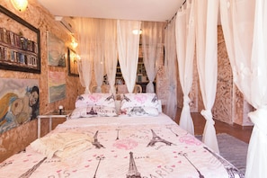 A bedroom with a bed adorned with Paris-themed bedding, a bookshelf with books, and a painting on the wall. - Villa Emily (Opatija)