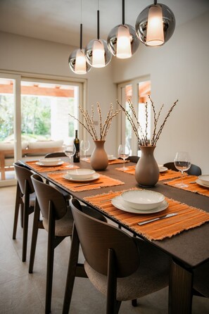 Un espace repas avec une longue table, des chaises et des lampes suspendues.
