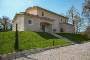 Une maison à deux étages avec une façade en pierre, une porte verte et un escalier menant à l’entrée.
