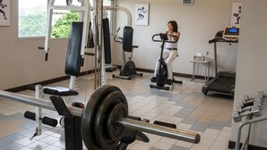 Une salle de sport équipée de matériel d’exercice, d’un tapis de course et d’une fenêtre donnant sur un espace verdoyant.