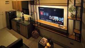 Un espace de vie moderne comprenant une cuisine, un coin repas et un salon avec un téléviseur.