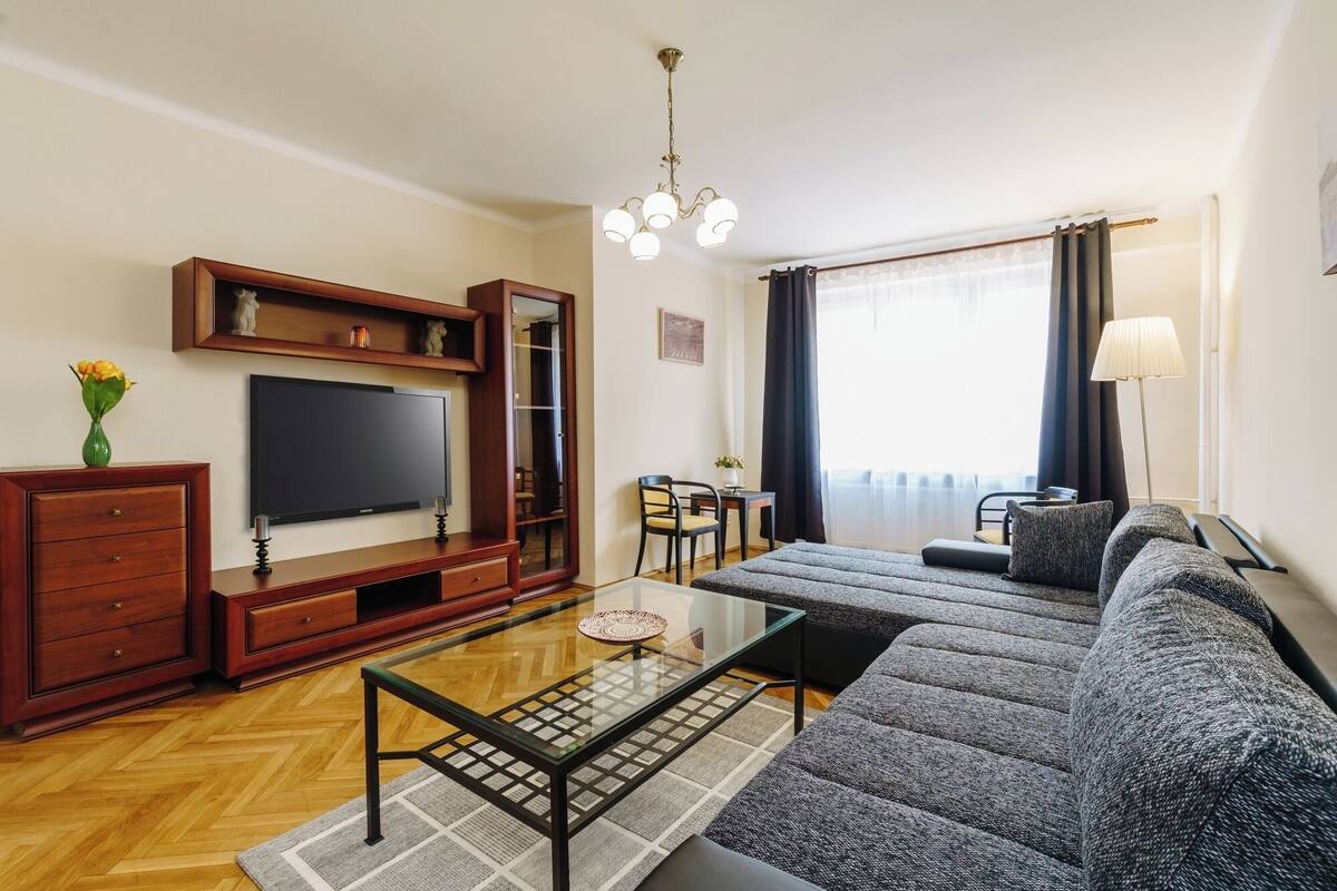 A modern living room with a sofa, TV, wooden cabinet, and a glass coffee table.