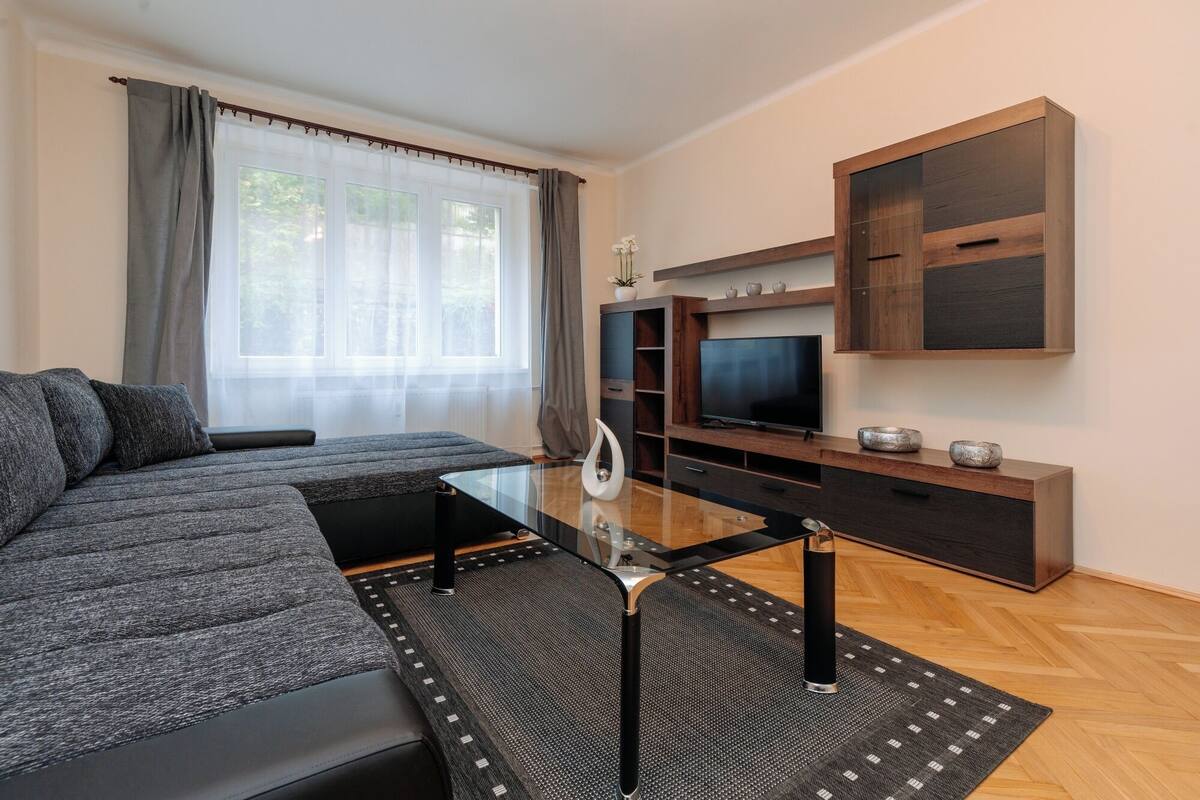 A modern living room with a sofa, TV, entertainment unit, and a glass coffee table.