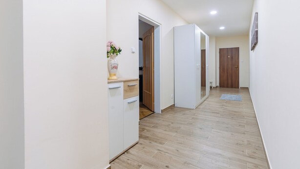 Un couloir doté d’un plancher en bois, de murs blancs et d’une porte donnant sur une pièce.