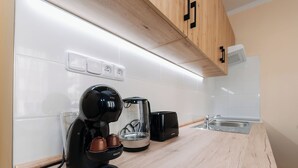 Une cuisine moderne équipée d’une machine à café, d’une bouilloire et d’un grille-pain sur le plan de travail.
